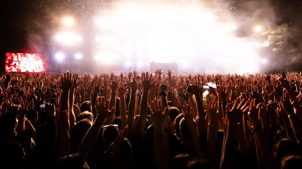 Público de mãos levantadas em show com luzes de palco