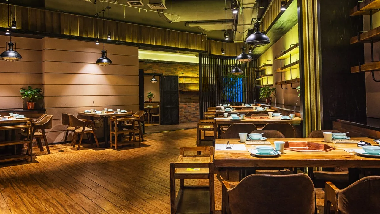Interior aconchegante de restaurante com mesas de madeira e iluminação quente
